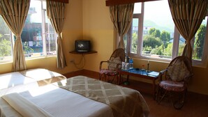 Una habitación de hotel con dos camas, una mesita con televisión y sillas.