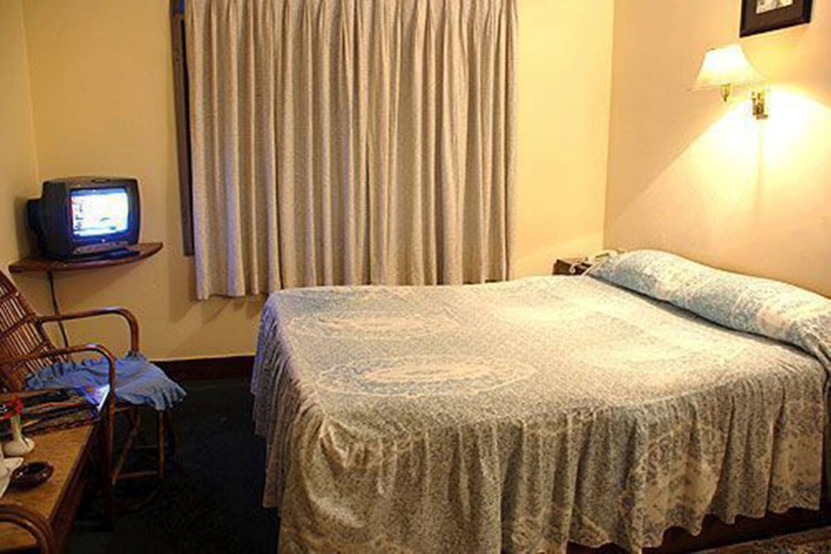 Une chambre d’hôtel avec un lit, un téléviseur posé sur une petite table, une lampe et une chaise.