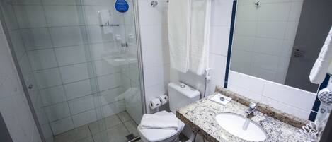 Une salle de bain moderne avec une douche à parois de verre, des toilettes blanches, un lavabo avec un plan de travail en granit et un miroir.