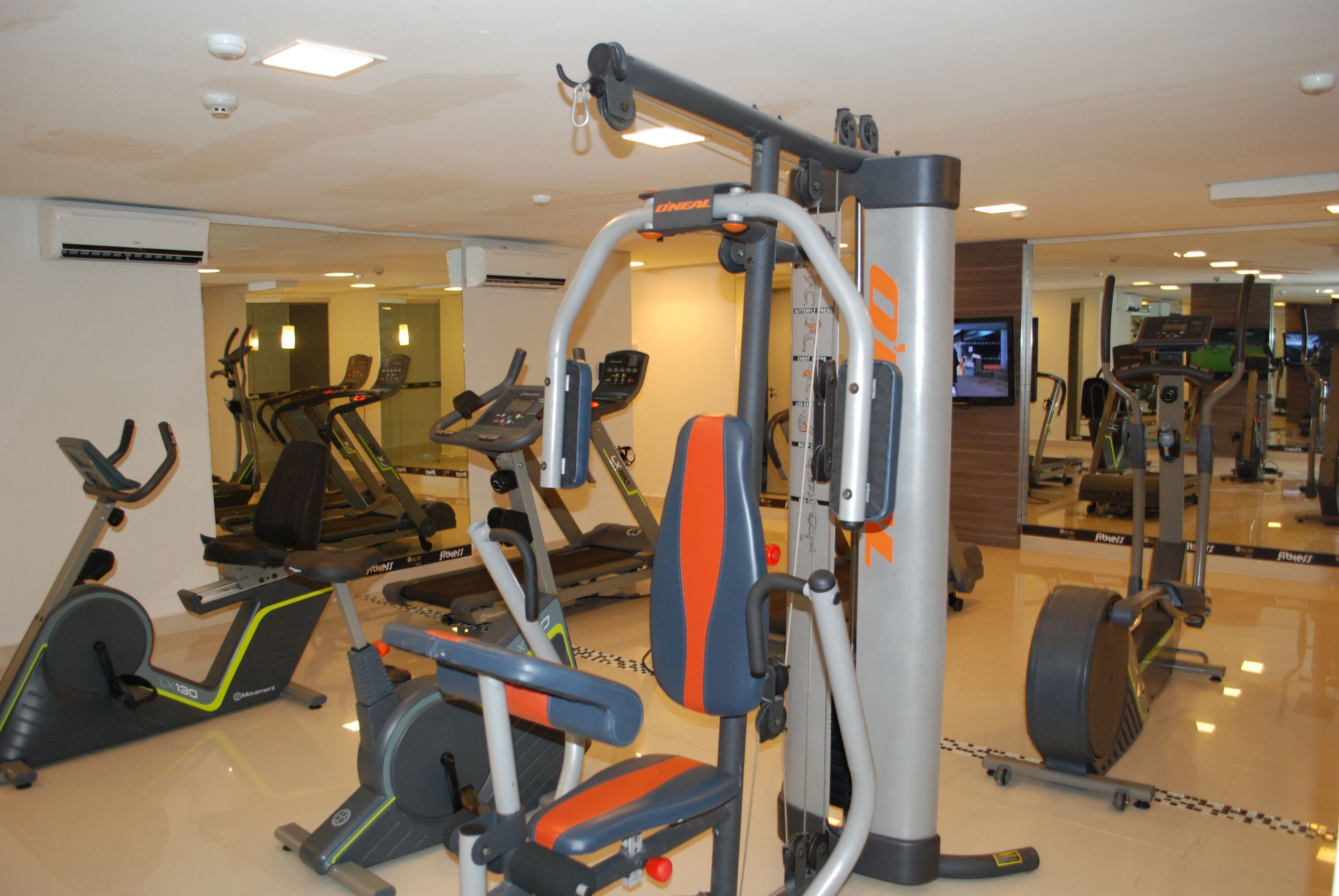 A gym with various exercise equipment, including treadmills, stationary bikes, and weight machines.
