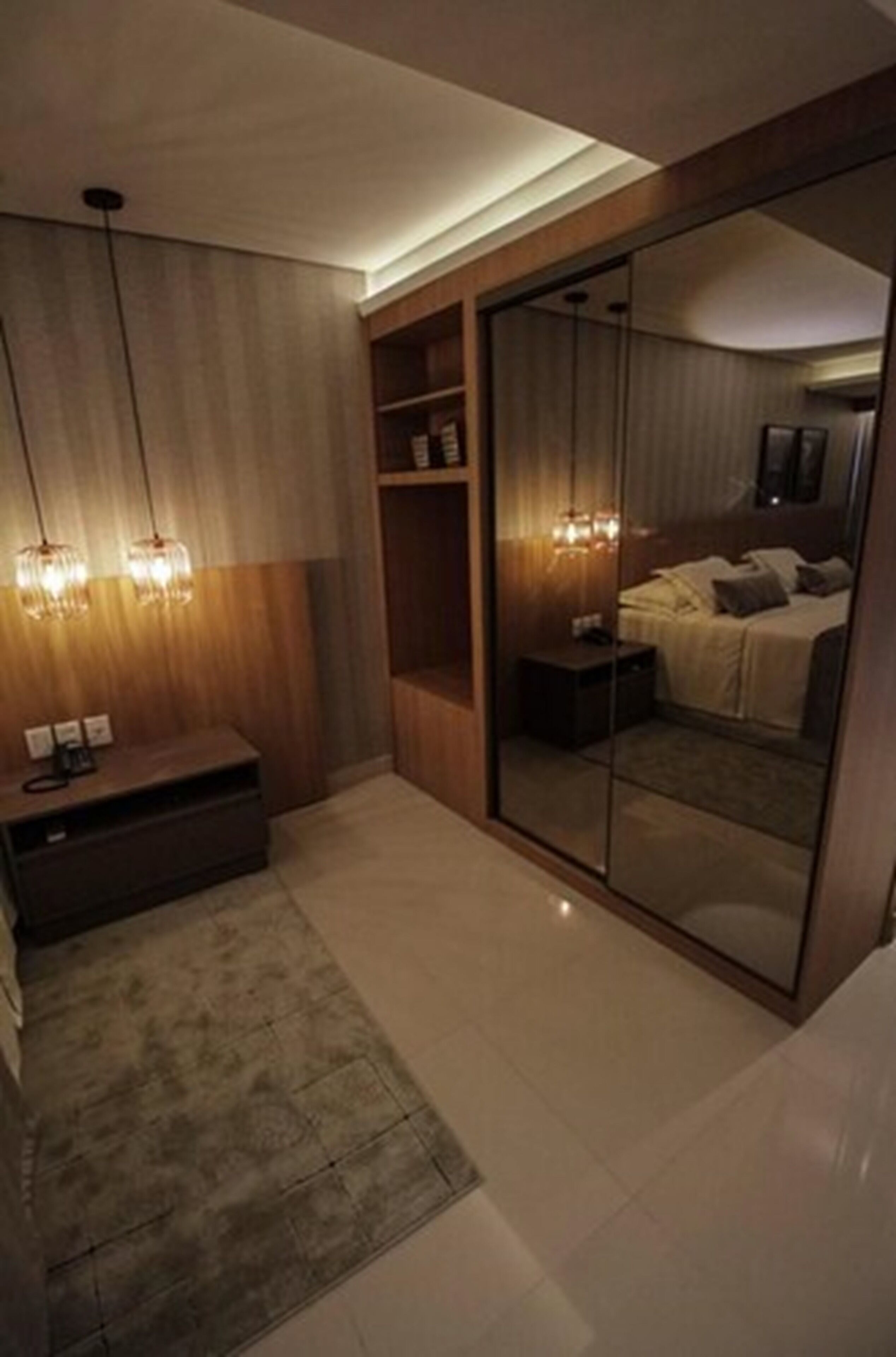 A modern bedroom with a large sliding glass door, a bedside table, a TV, and a rug.