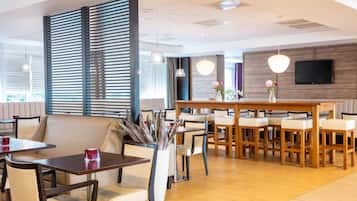 A modern dining area with a wooden bar, cushioned seating, and pendant lighting.