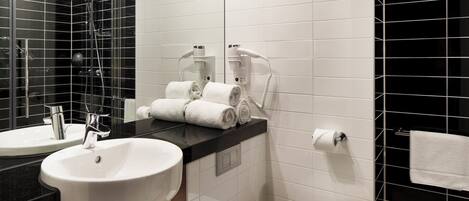 A modern bathroom with a sink, mirror, towel rack, and a shower area.