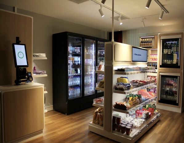 Een moderne winkel met koelvitrines, een digitale kiosk en diverse verpakte producten.
