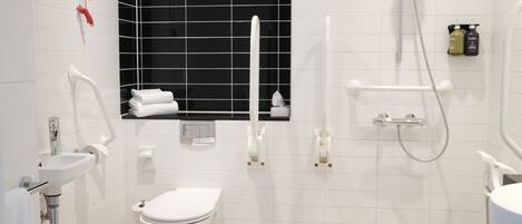 Een moderne badkamer met een wit toilet, een wastafel, een douche en een raam met een zwarte omlijsting.