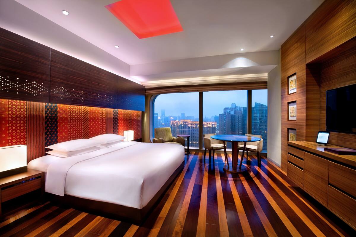 Quarto de hotel com uma cama grande, área de refeições e vista para a cidade.