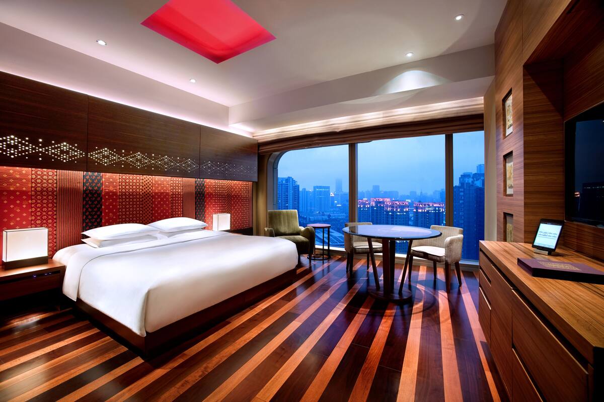 Quarto de hotel com uma cama grande, uma escrivaninha e vista para a cidade.