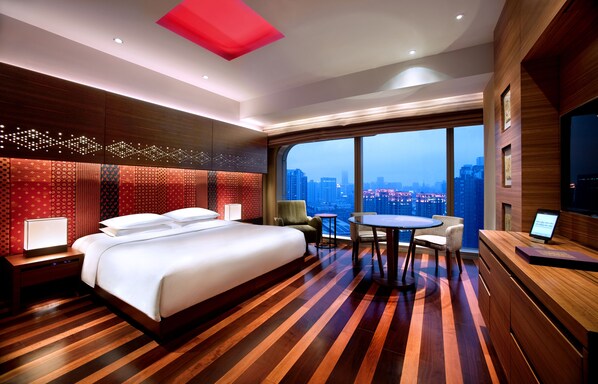 Une chambre d’hôtel avec un grand lit, un bureau et une vue sur le paysage urbain.