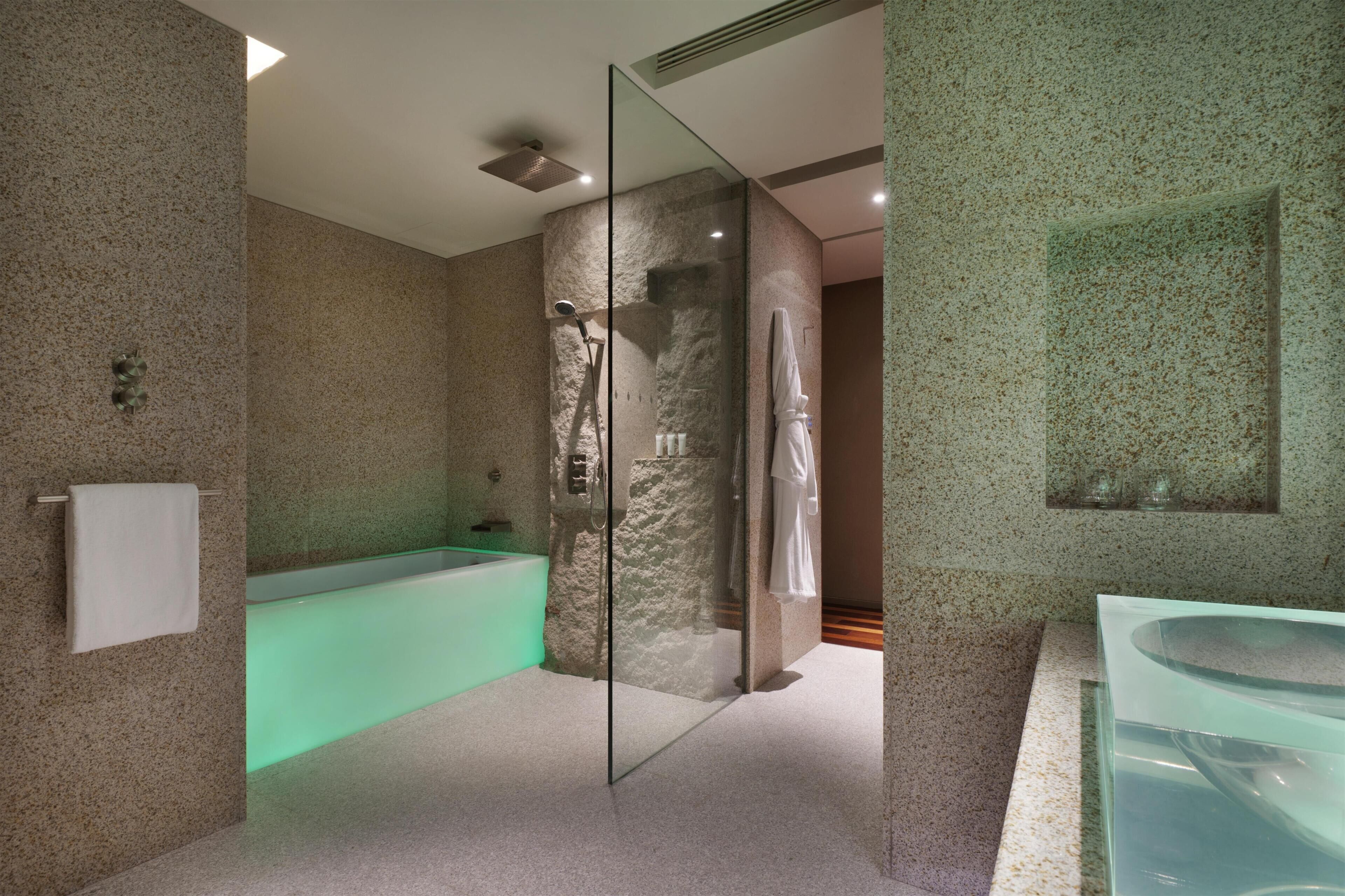 A modern bathroom with a glass-enclosed shower, a standalone bathtub, and a glass sink.