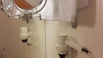 A bathroom with a mirror, towel rack, hair dryer, and toiletries.