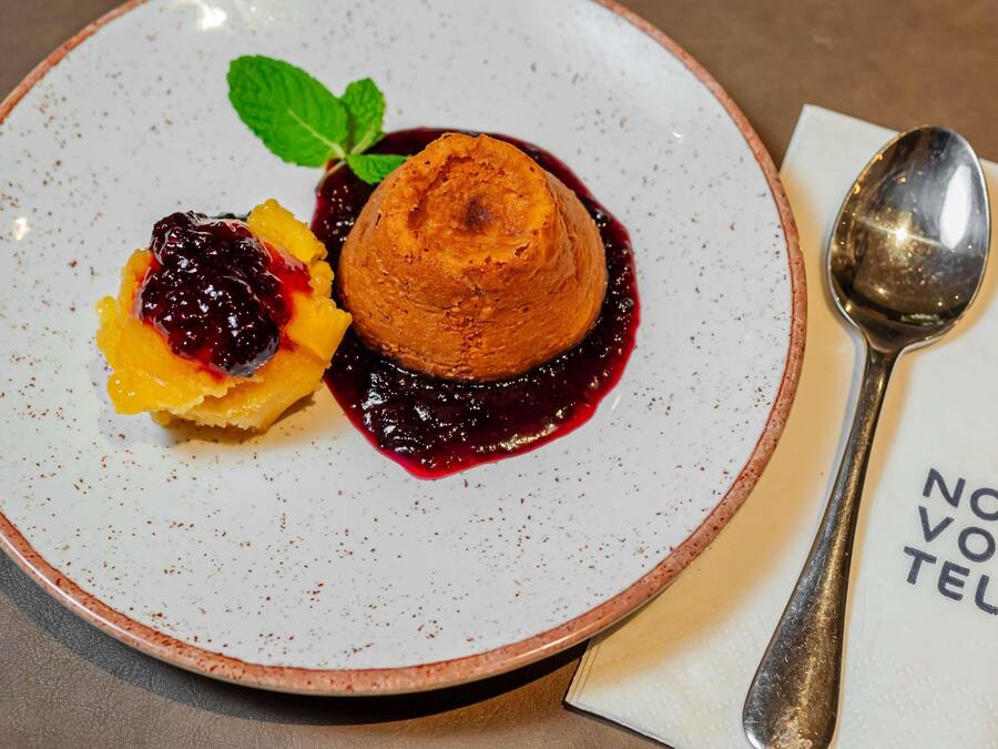 A dessert plate with a scoop of ice cream and a fruit compote, accompanied by a spoon and a napkin.