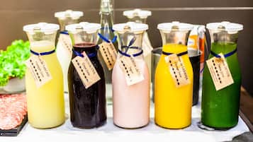 A variety of colorful beverages in glass bottles with labels, displayed on a counter.