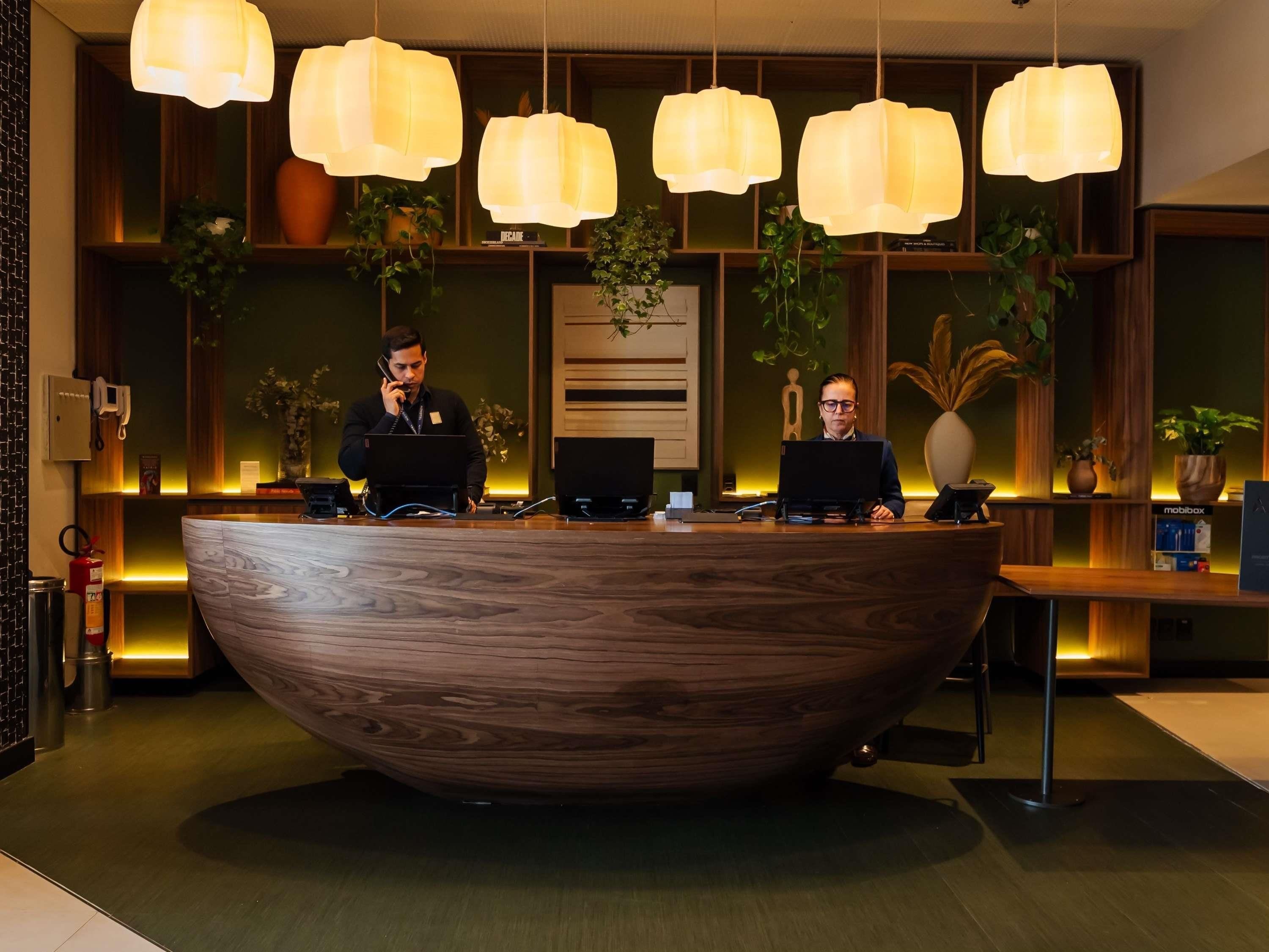 A reception desk with a wooden finish, multiple computer stations, and hanging pendant lights.