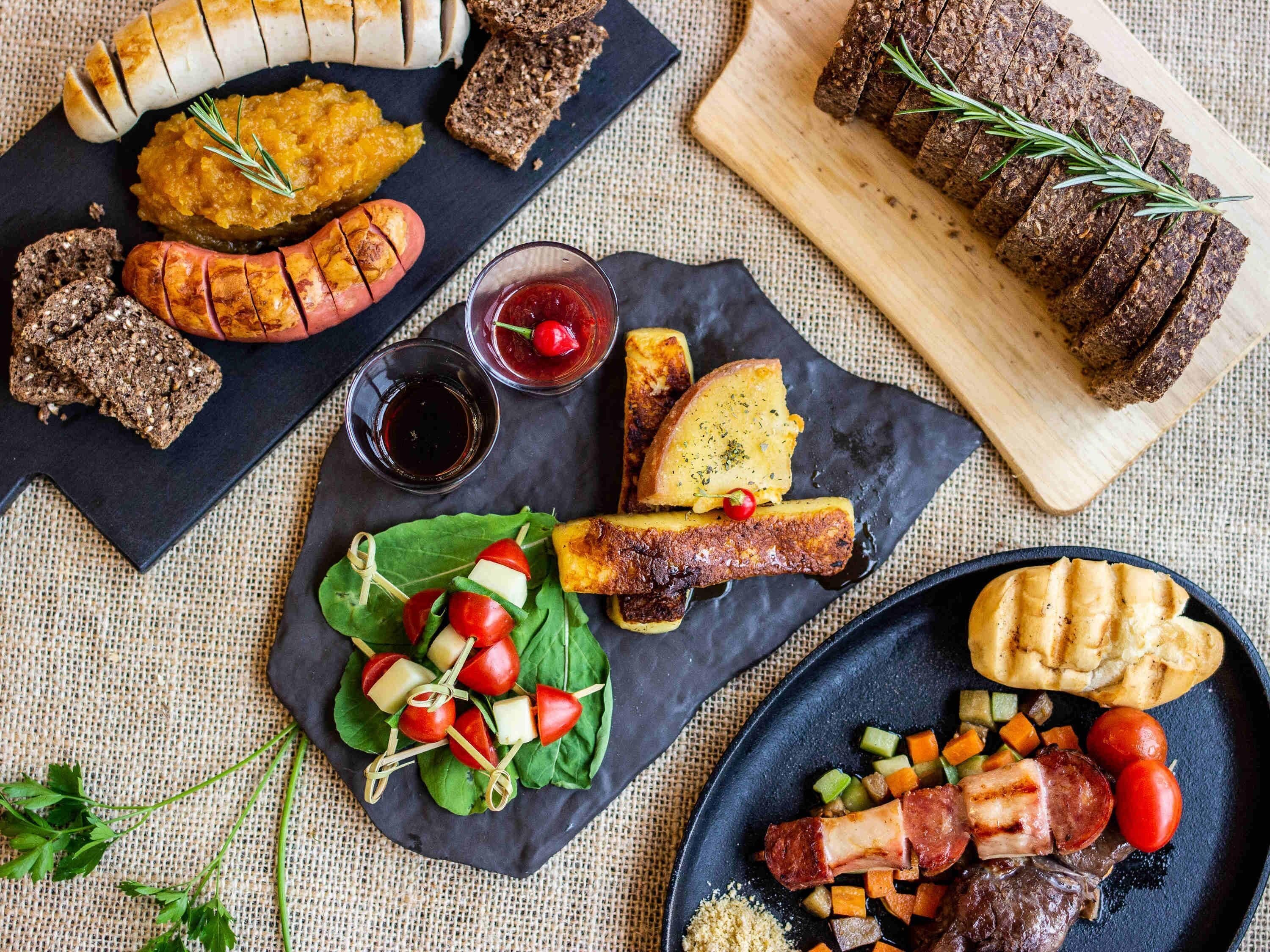 Ett urval av matvaror, inklusive korv, bröd och en tallrik med kött och grönsaker.