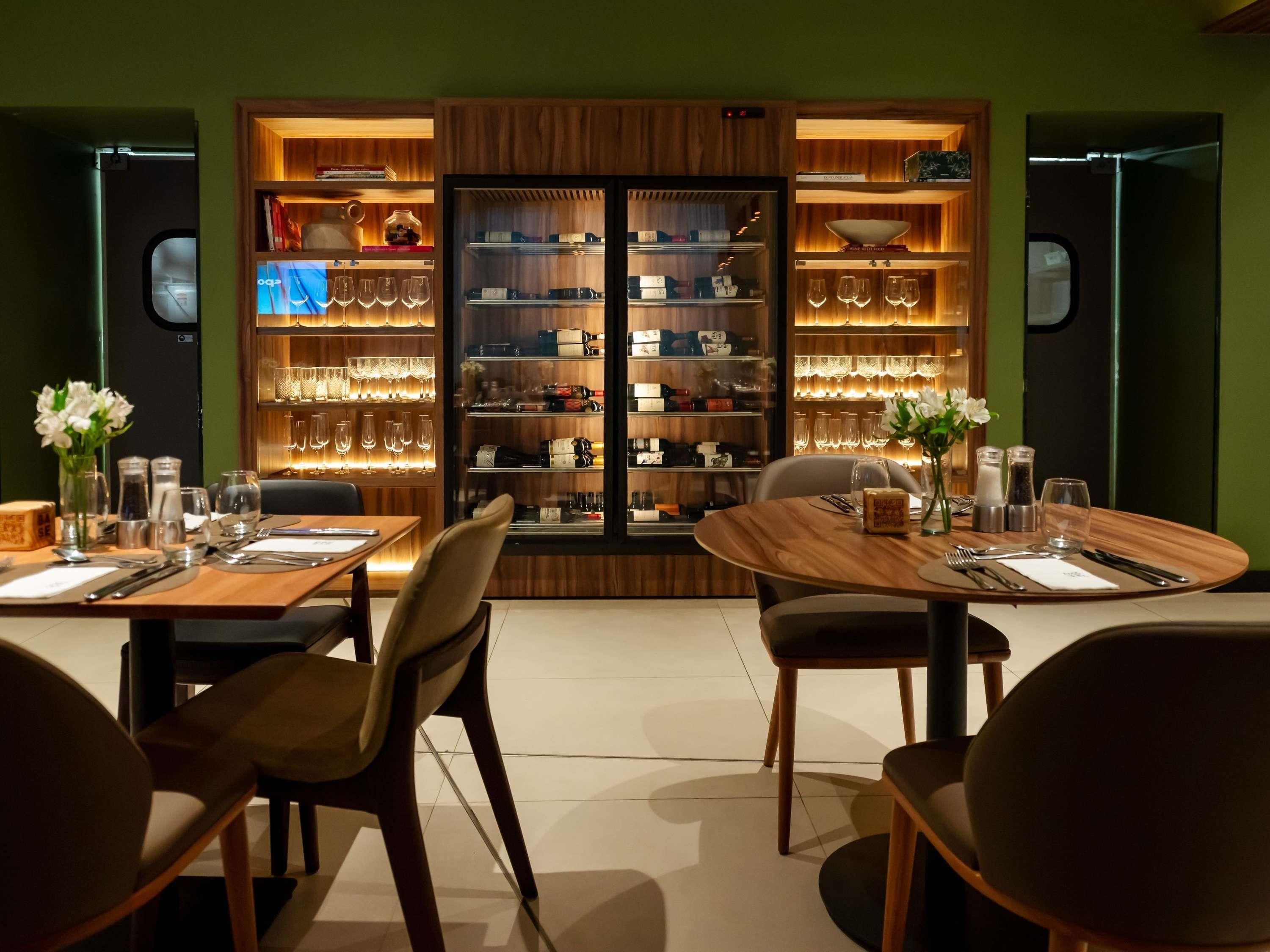 A restaurant with a wooden interior, multiple tables, and a wine display.