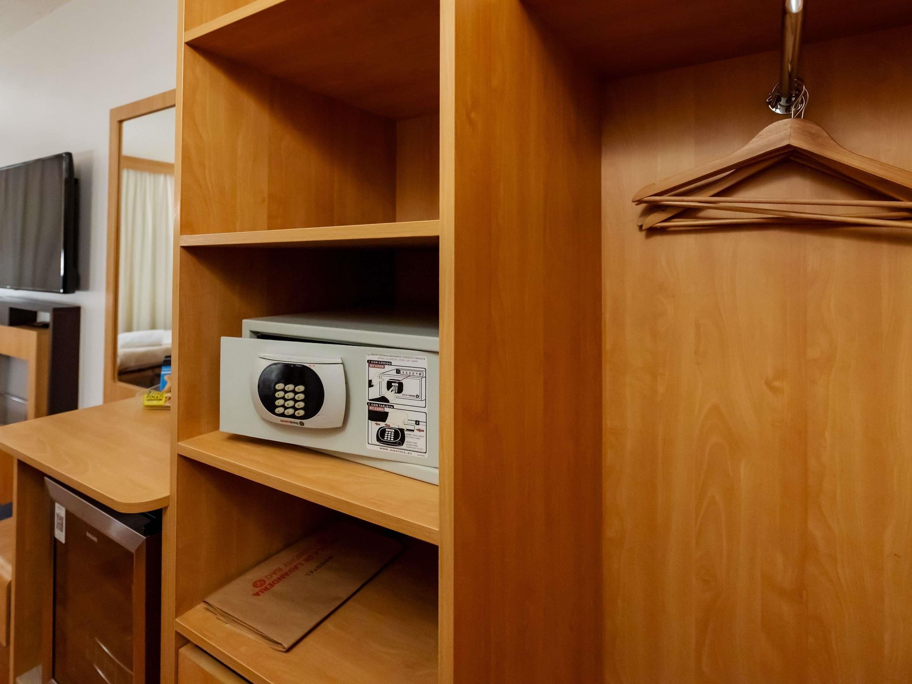 Un armario de madera con una barra para colgar, un estante con un dispositivo blanco y un cajón pequeño.