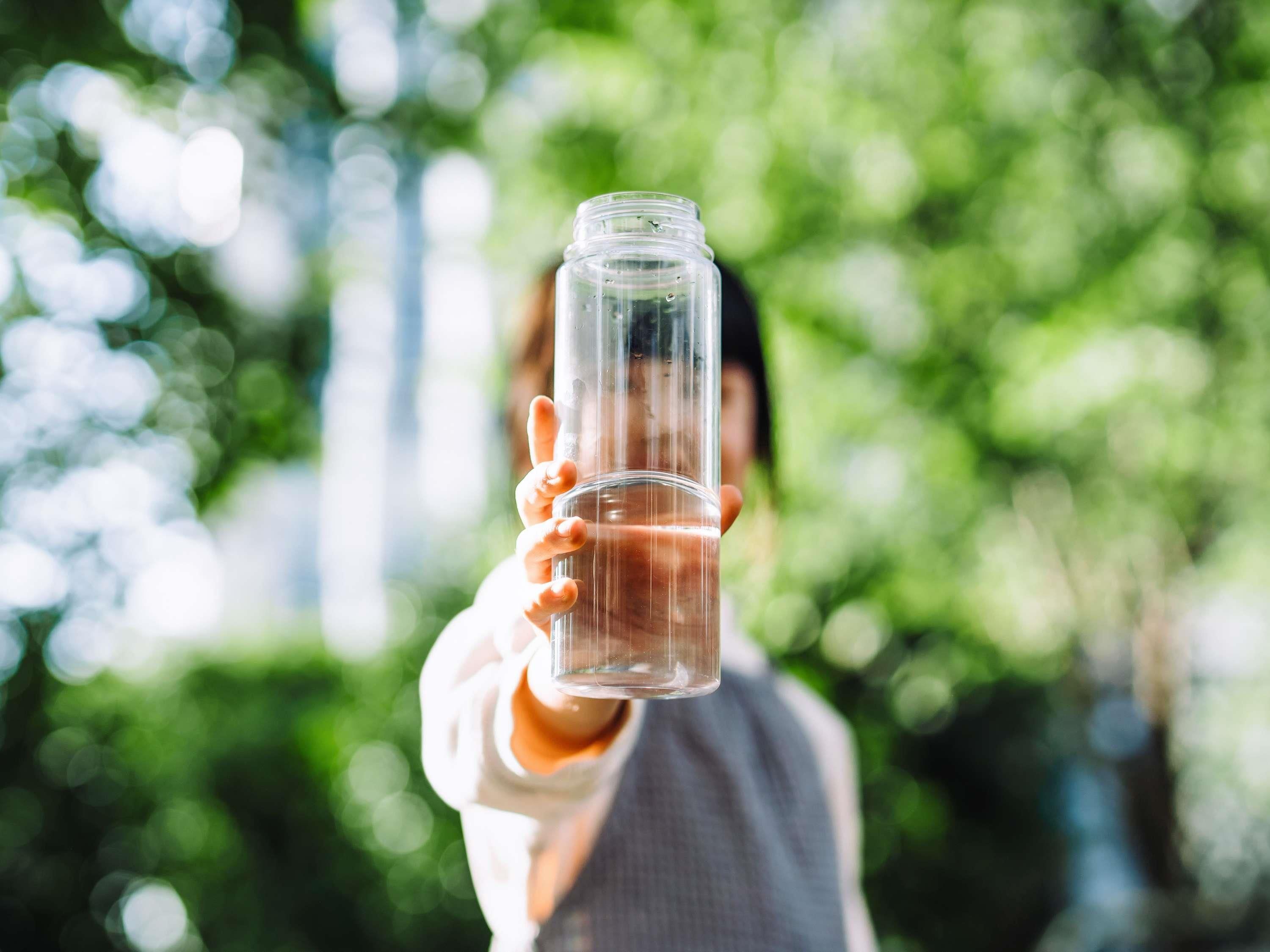 A person holding a clear glass bottle.