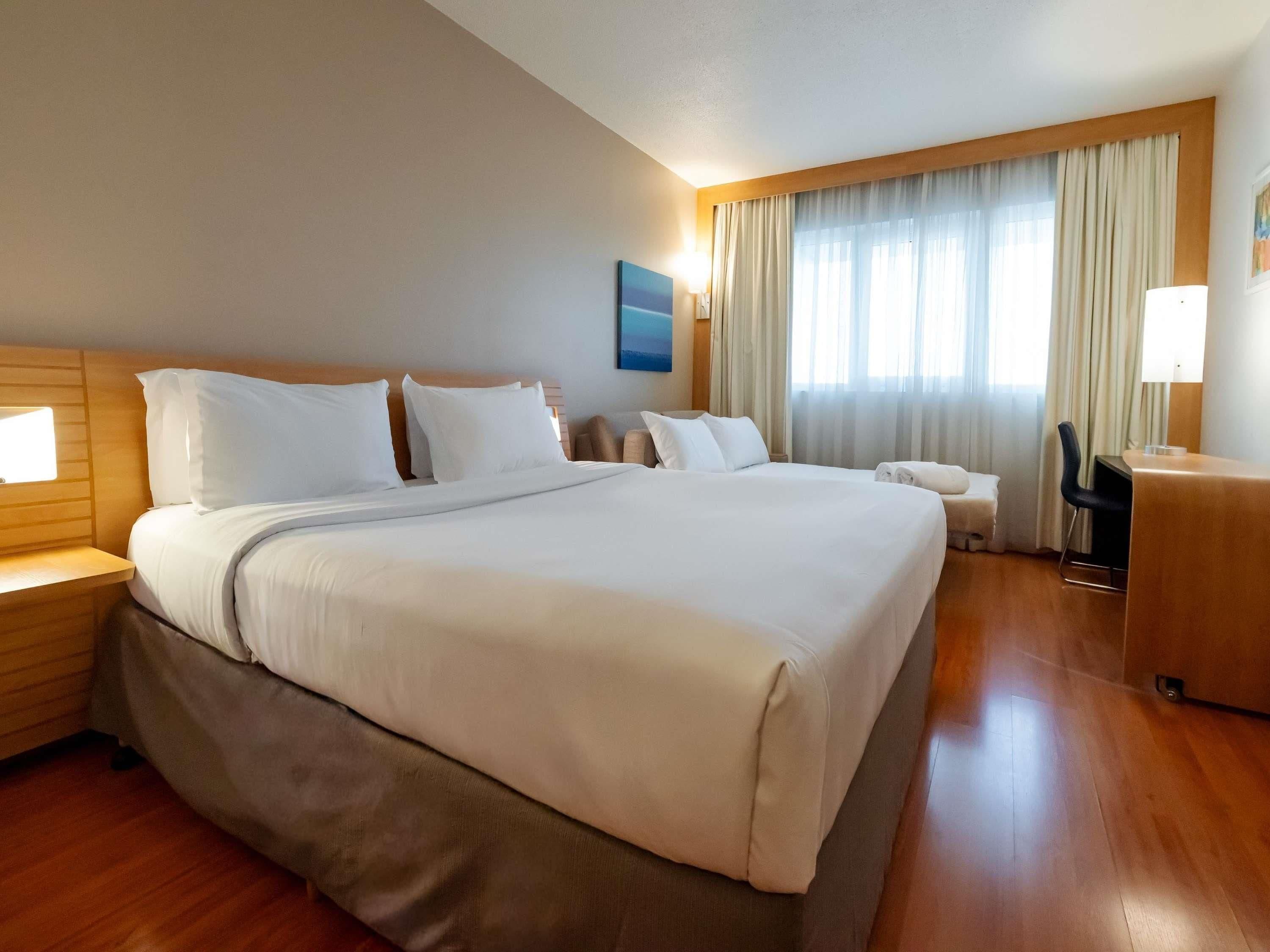 A hotel room with a large bed, bedside tables, a desk, and a chair.