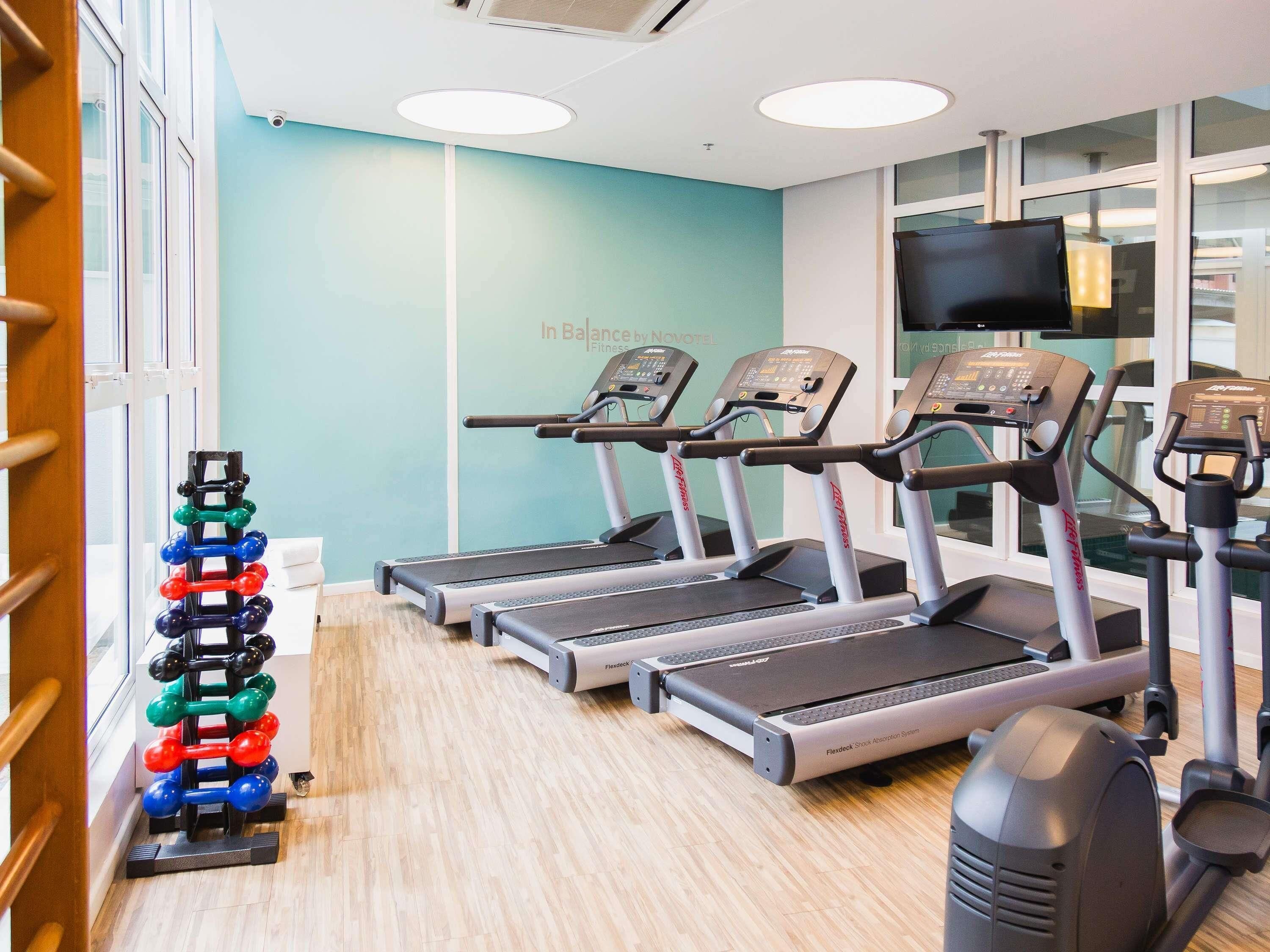 Un gimnasio con cintas de correr, un soporte para mancuernas y un televisor.