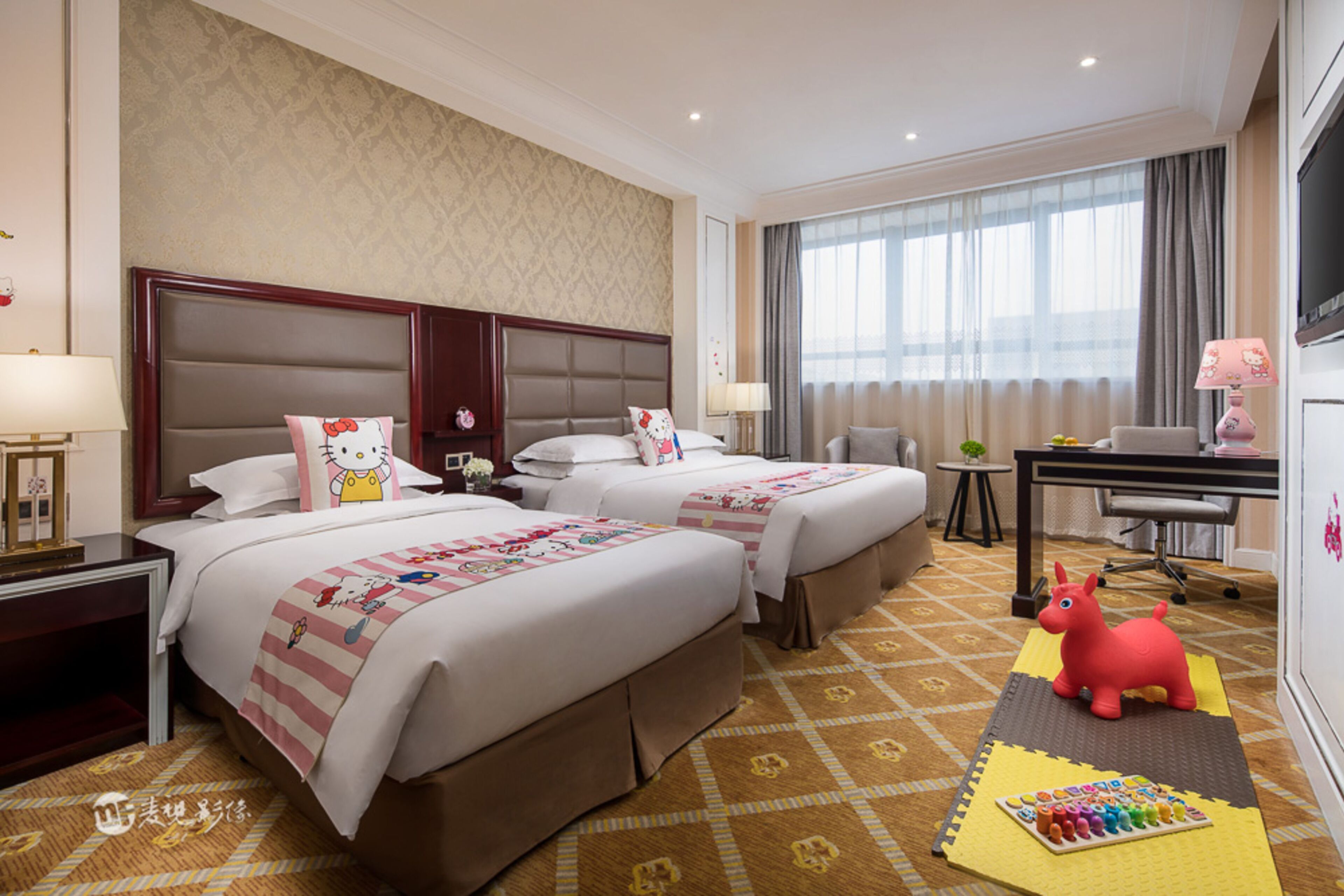 Een hotelkamer met twee bedden, een bureau en een televisie.
