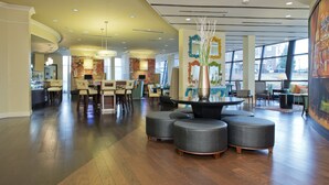 Um hall amplo com um espaço de bar moderno, assentos confortáveis e grandes janelas que oferecem iluminação natural.