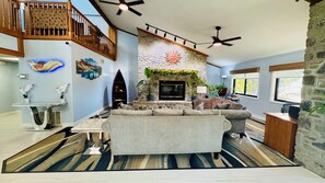 A spacious living room with a stone fireplace, a large sofa, and a dining area with a marble table. - Regency Inn And Suites (Stilwell)