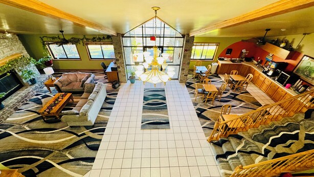 A spacious lobby with a central chandelier, a staircase, and a seating area with sofas and a coffee table.