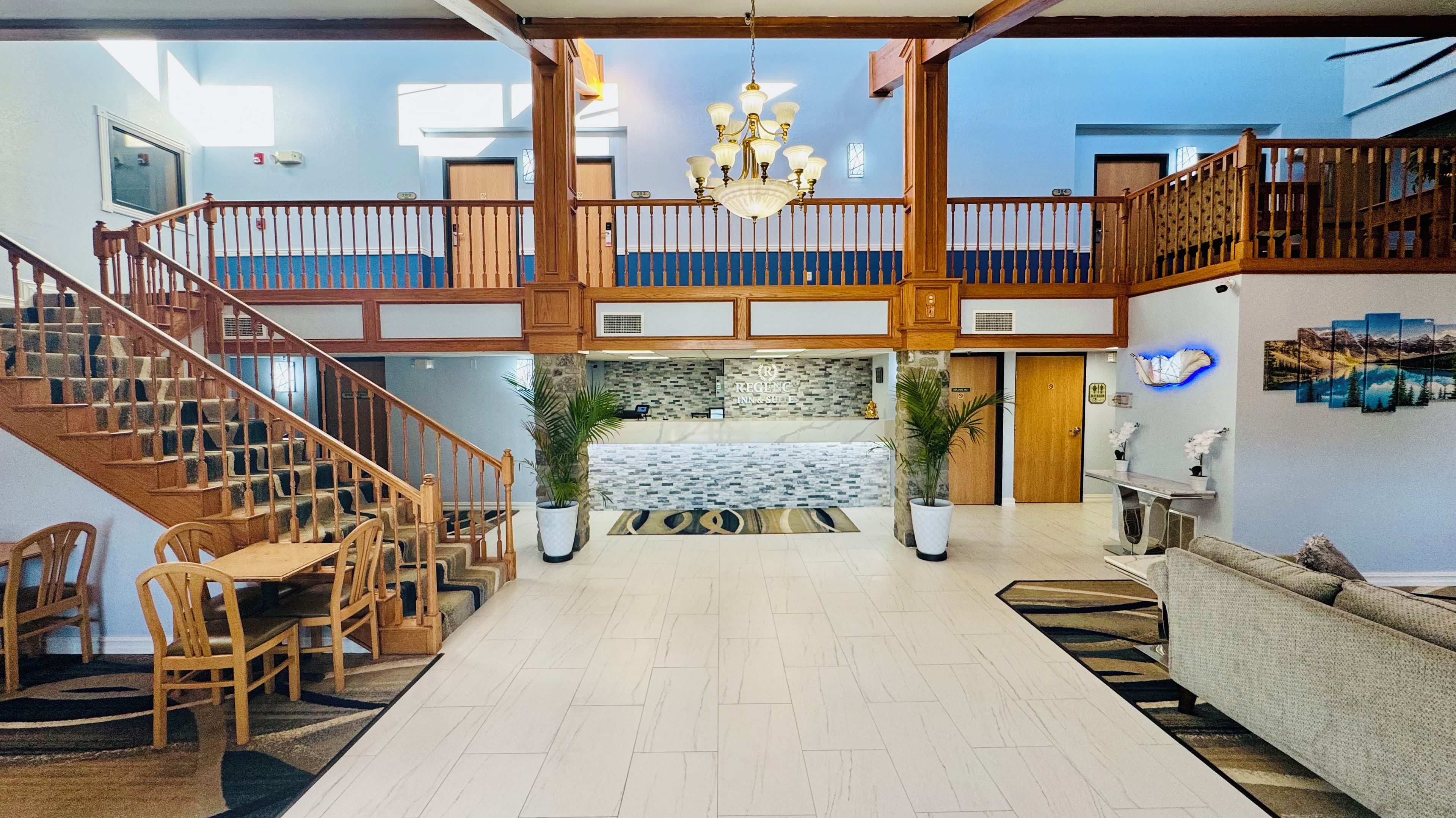 A spacious lobby with a staircase, wooden furniture, and a chandelier.