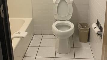 A bathroom with a toilet, a shower, and a towel rack with towels.