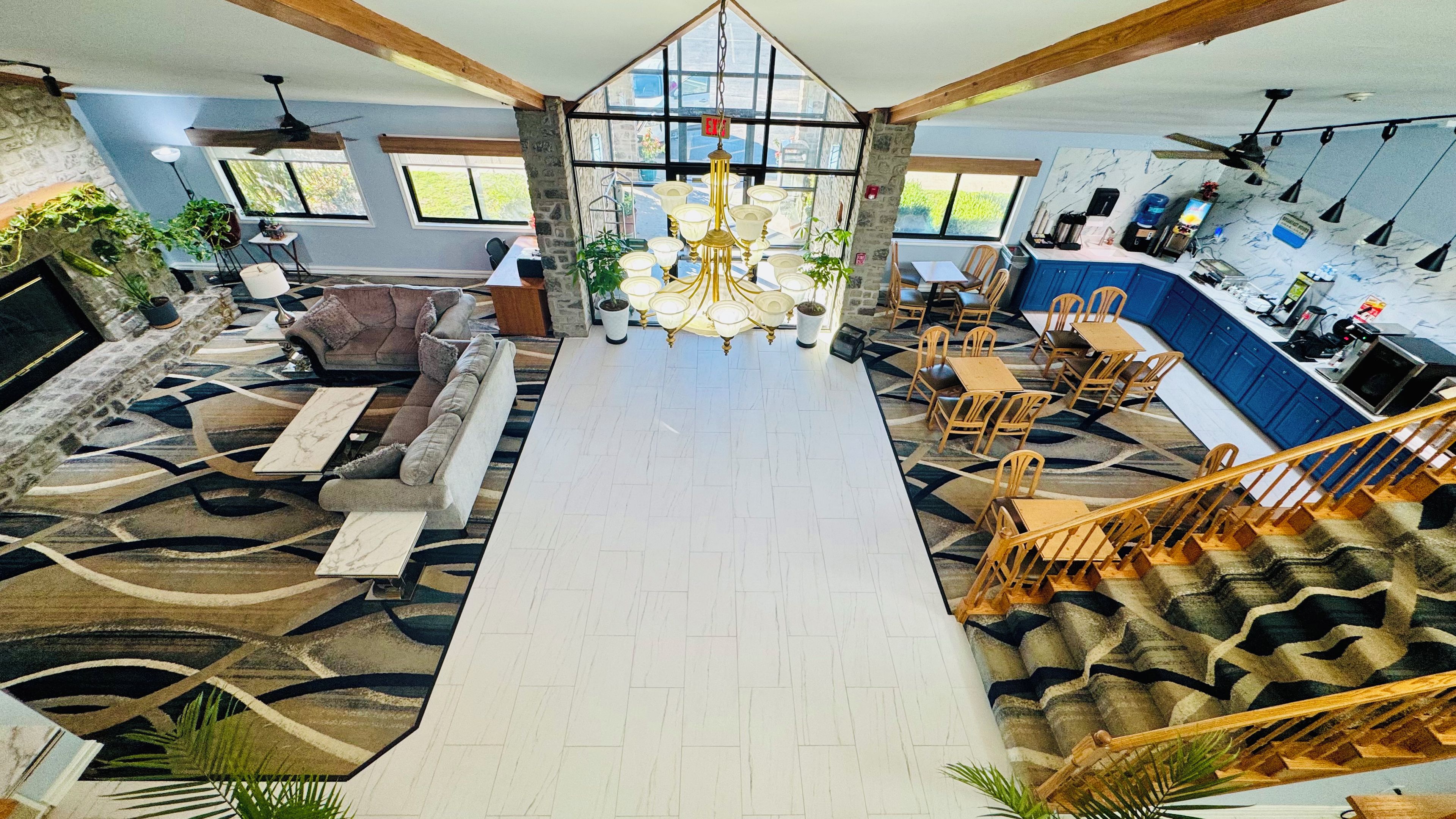 A spacious living area with a large chandelier, a staircase, and a kitchen area.