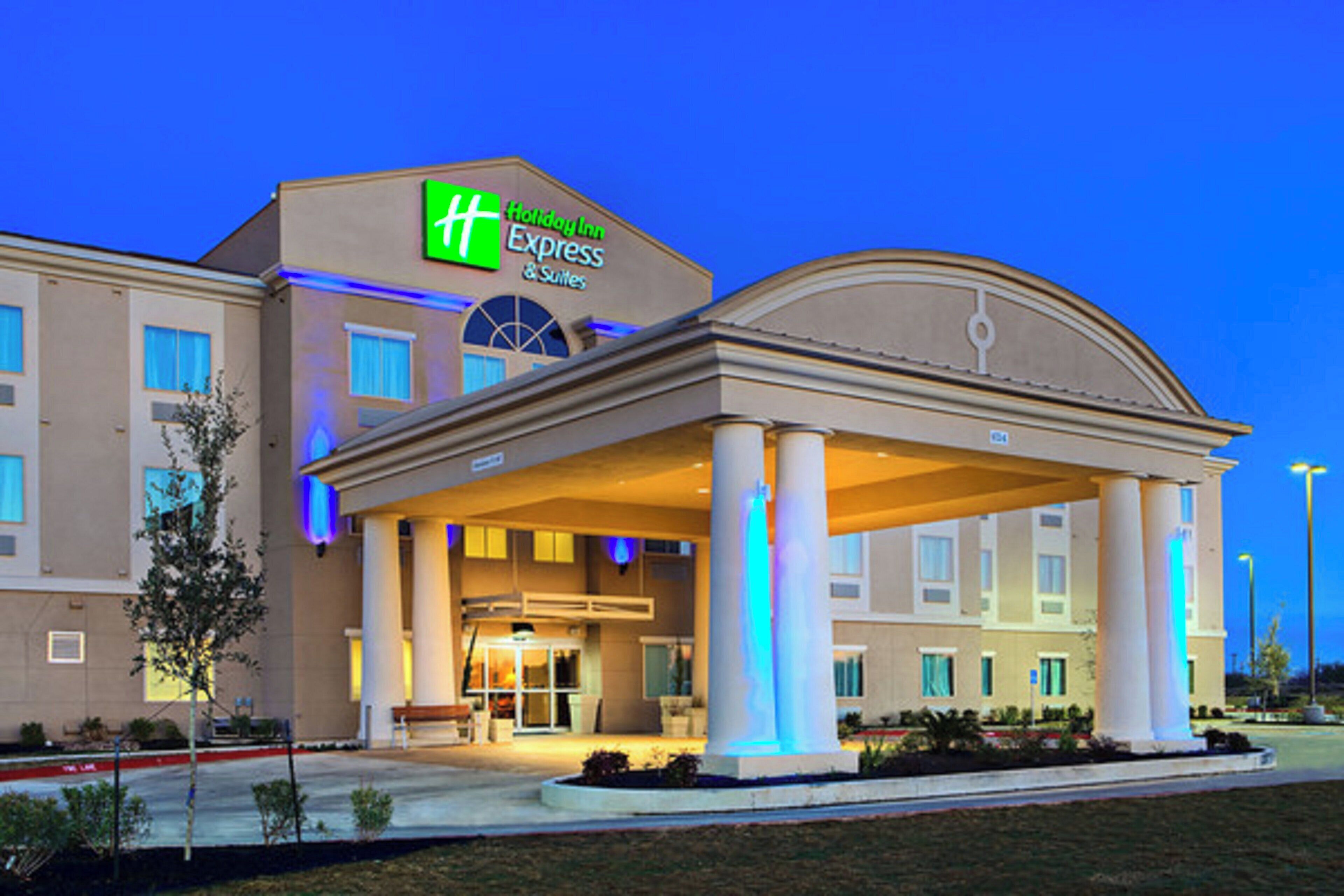 Un hôtel Holiday Inn Express & Suites doté d’une entrée abritée et offrant une vue sur un ciel dégagé.