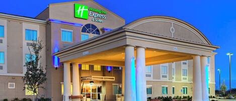 Un hotel Holiday Inn Express & Suites con entrada cubierta y cielo despejado.