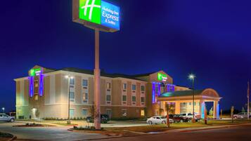 A Holiday Inn Express & Suites hotel with a large illuminated sign, a covered entrance, and a parking lot.