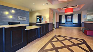 A hotel reception area with a reception desk, a digital display, and a seating area with a patterned floor. - Holiday Inn Express & Suites Cotulla by IHG (Cotulla)