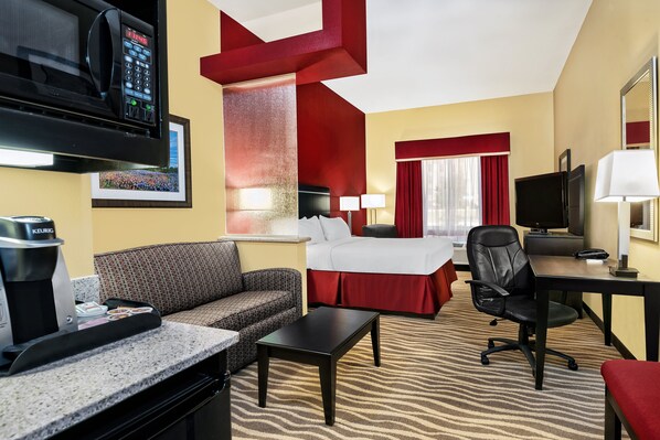 A hotel room with a bed, a sofa, a desk, a chair, a coffee maker, a TV, and a microwave. - Holiday Inn Express & Suites Cotulla by IHG (Cotulla)