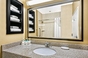 A bathroom with a granite countertop, a sink, a mirror, and a towel rack with neatly folded towels. - Holiday Inn Express & Suites Cotulla by IHG (Cotulla)