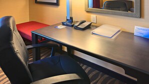A hotel room with a desk, a telephone, a notepad, a lamp, a chair, and a red bench. - Holiday Inn Express & Suites Cotulla by IHG (Cotulla)
