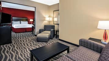A hotel room with a bed, a TV, a desk, a chair, and a sofa.