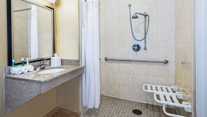 A bathroom with a sink, mirror, shower, and grab bars. - Holiday Inn Express & Suites Cotulla by IHG (Cotulla)