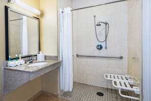A bathroom with a sink, mirror, shower, and grab bars. - Holiday Inn Express & Suites Cotulla by IHG (Cotulla)