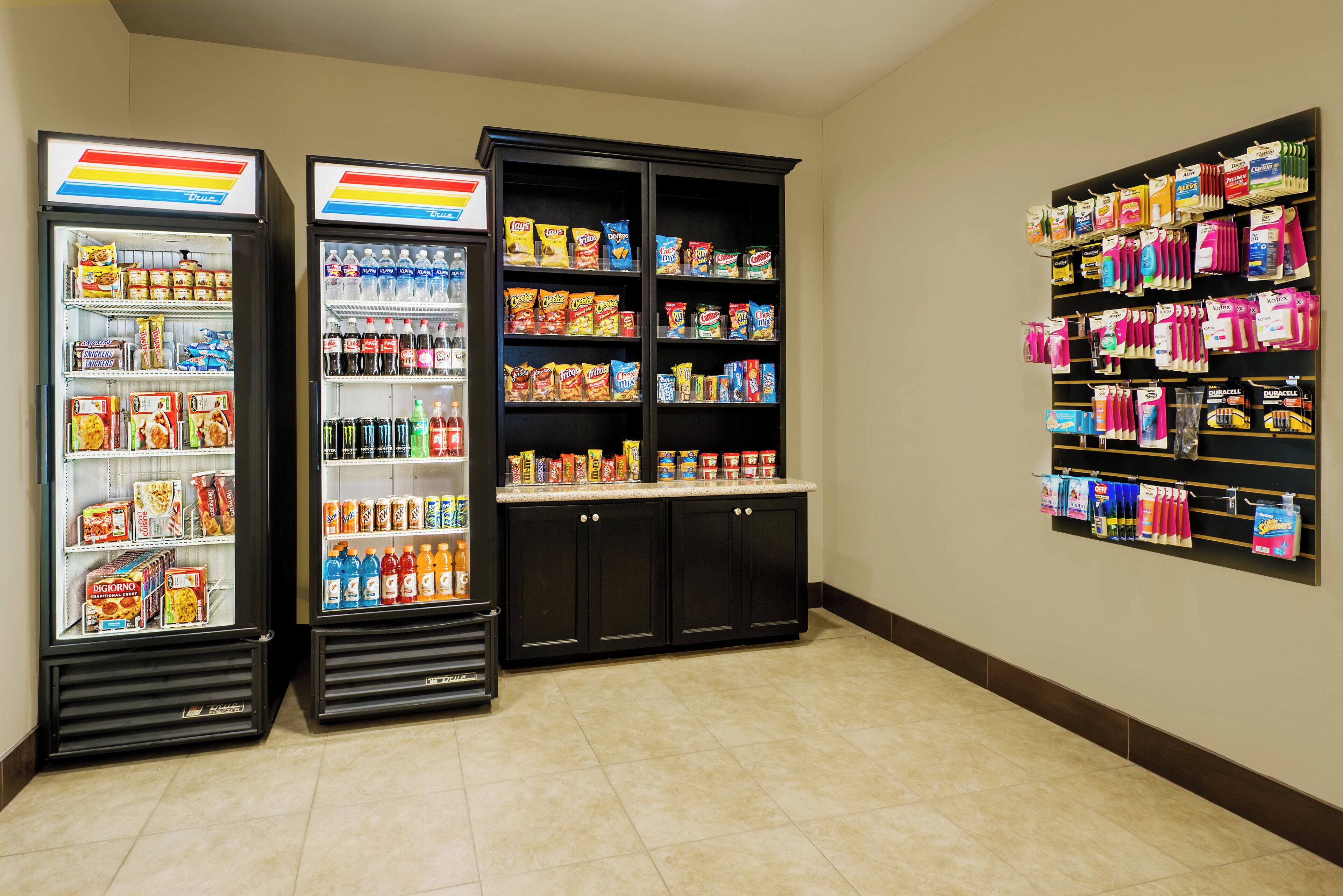 A vending area with snack machines, a beverage cooler, and a shelf with personal care items.