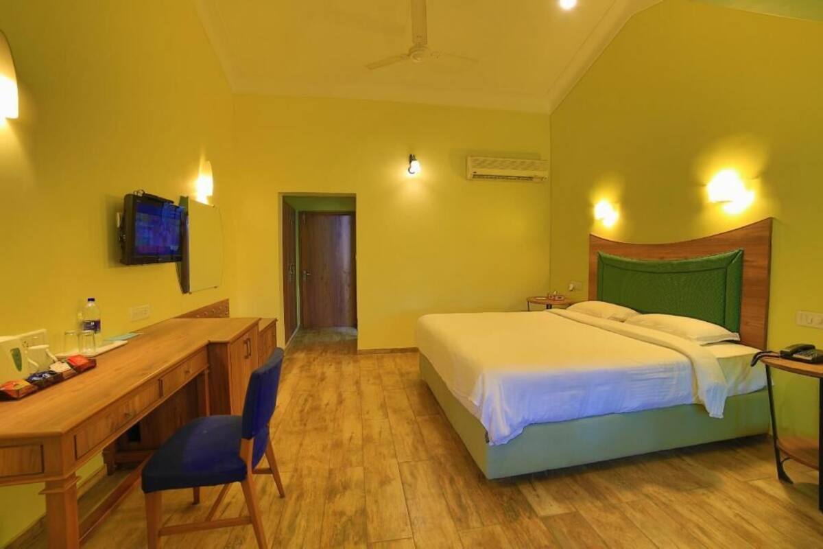 A hotel room with a bed, desk, chair, television, and a door leading to another room.