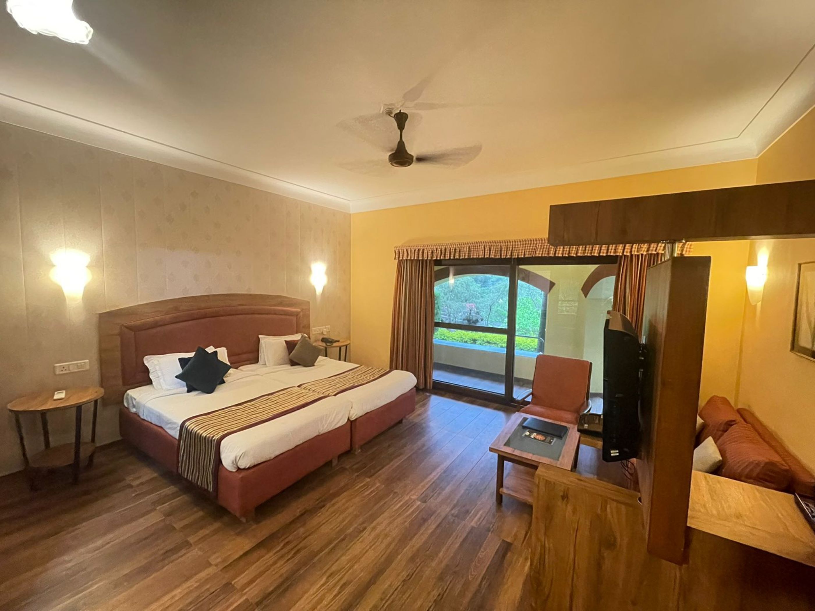 A hotel room with a large bed, a desk, a chair, and a view of the outdoors.