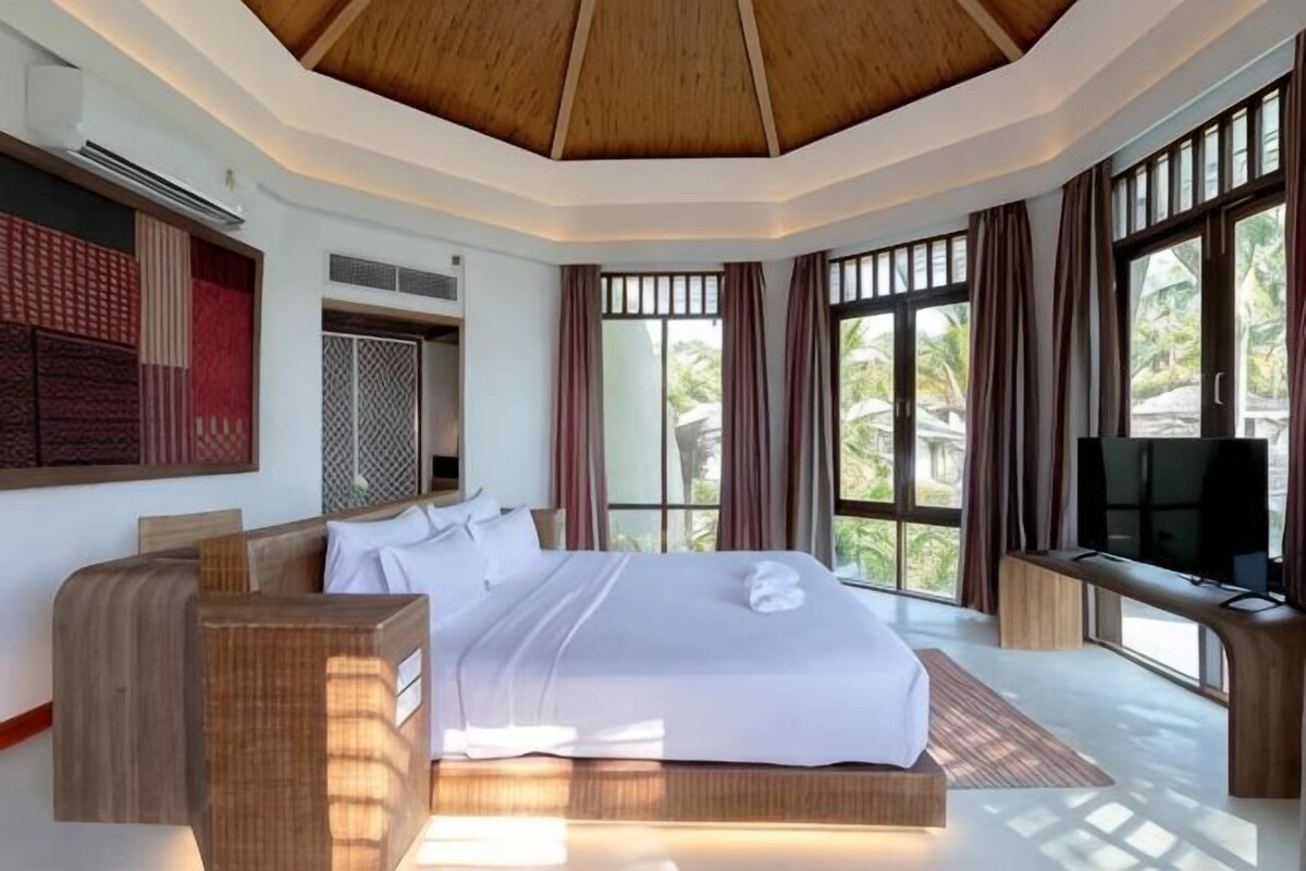 Une chambre d’hôtel moderne, dotée d’un grand lit, d’une télévision et de grandes fenêtres.