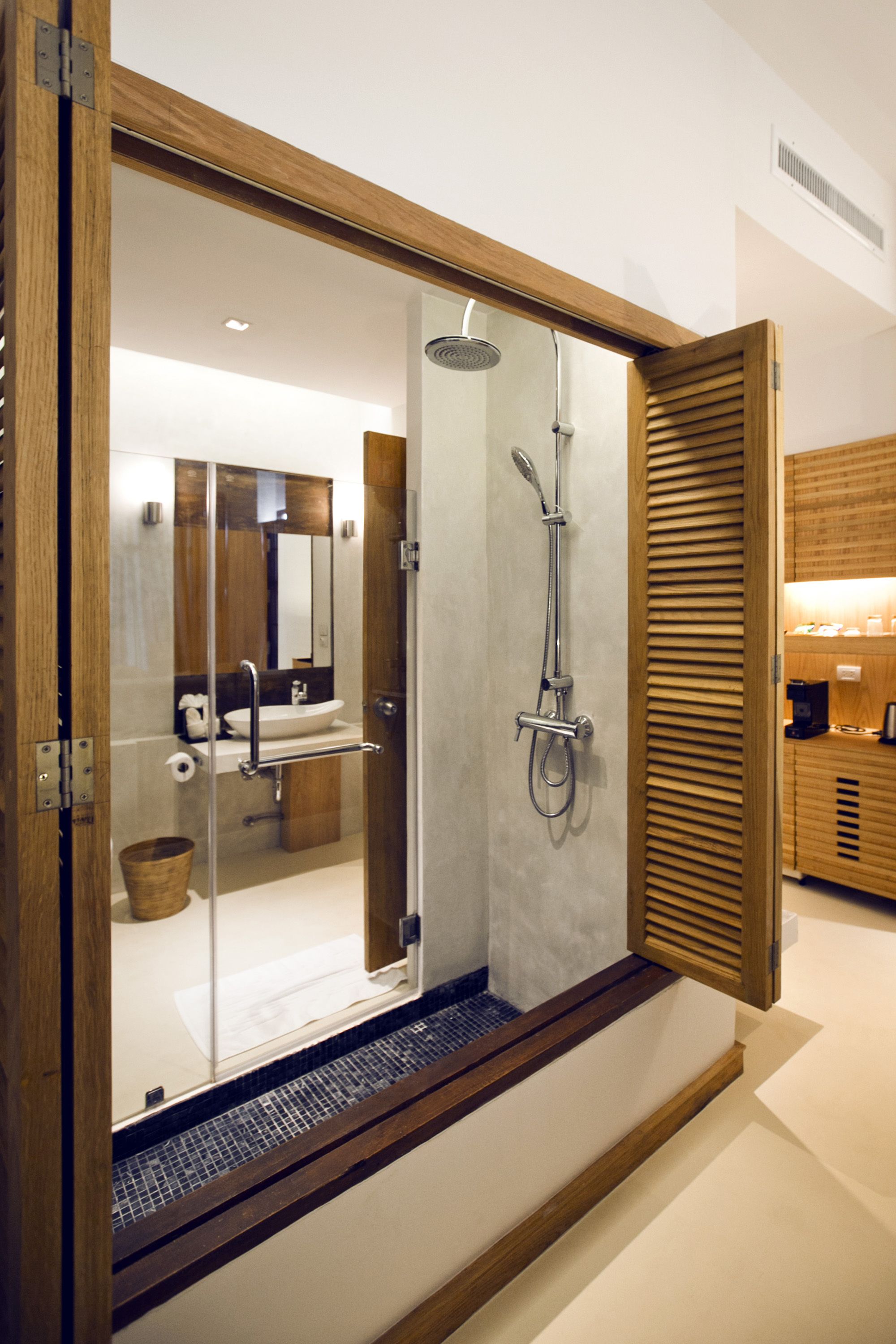 Un baño moderno con cabina de ducha de cristal, paneles de madera y zona de lavamanos visible.