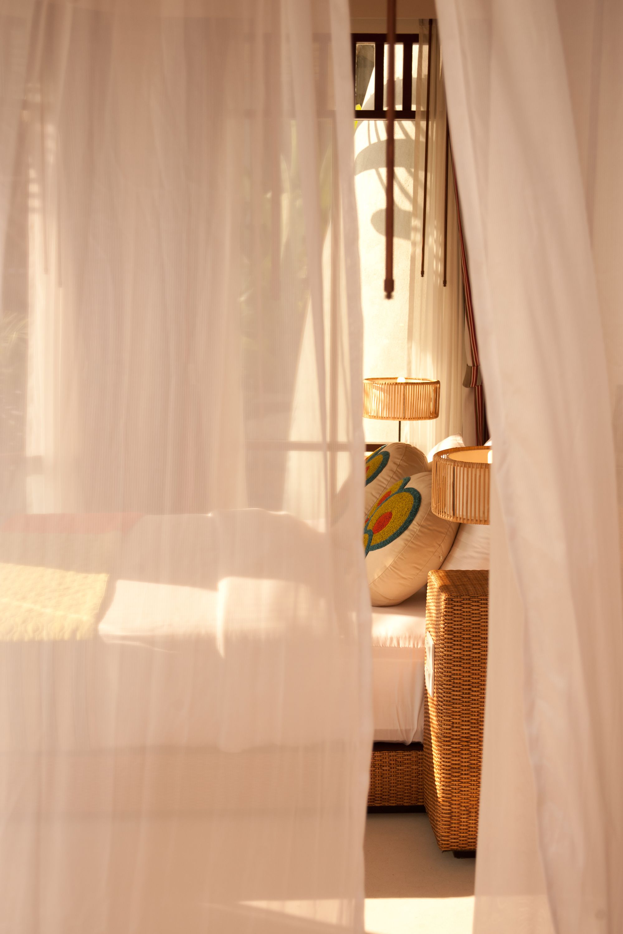 Ein Schlafzimmer mit einem Bett, einem Korbstuhl und einer Lampe.