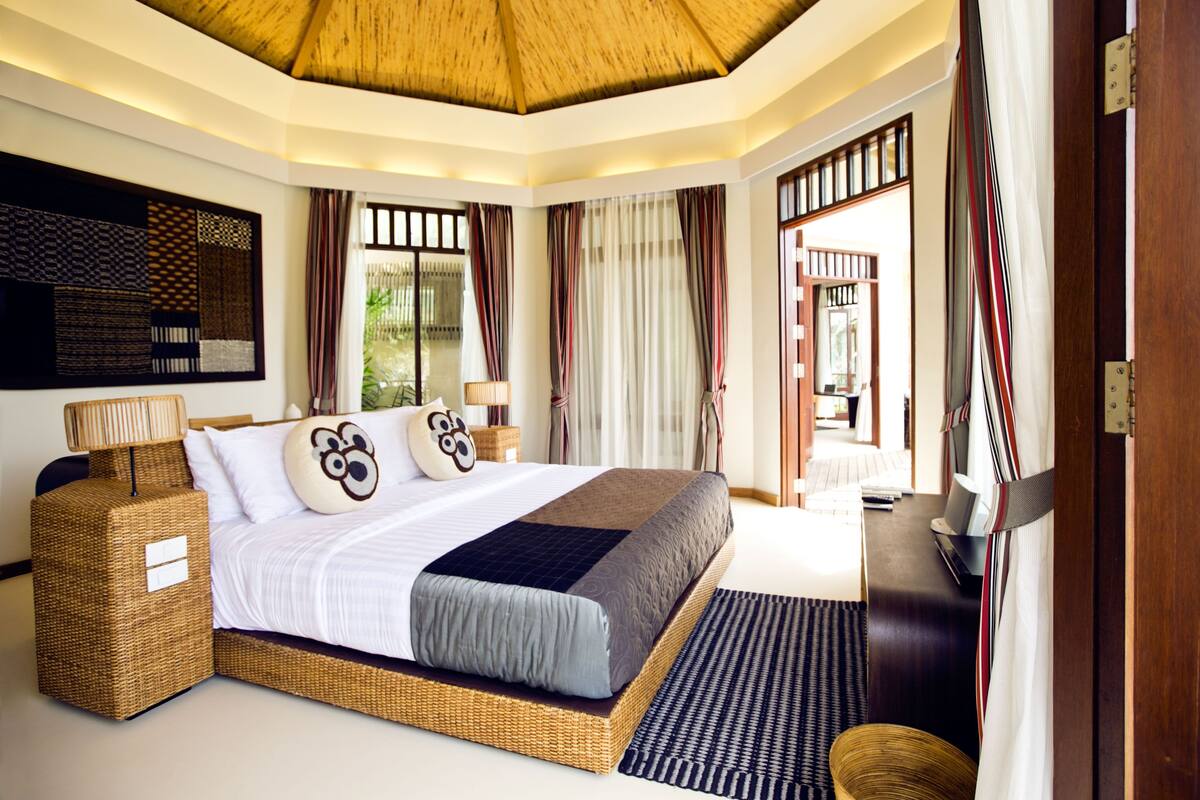 A spacious bedroom with a large bed, a woven headboard, and a ceiling fan.