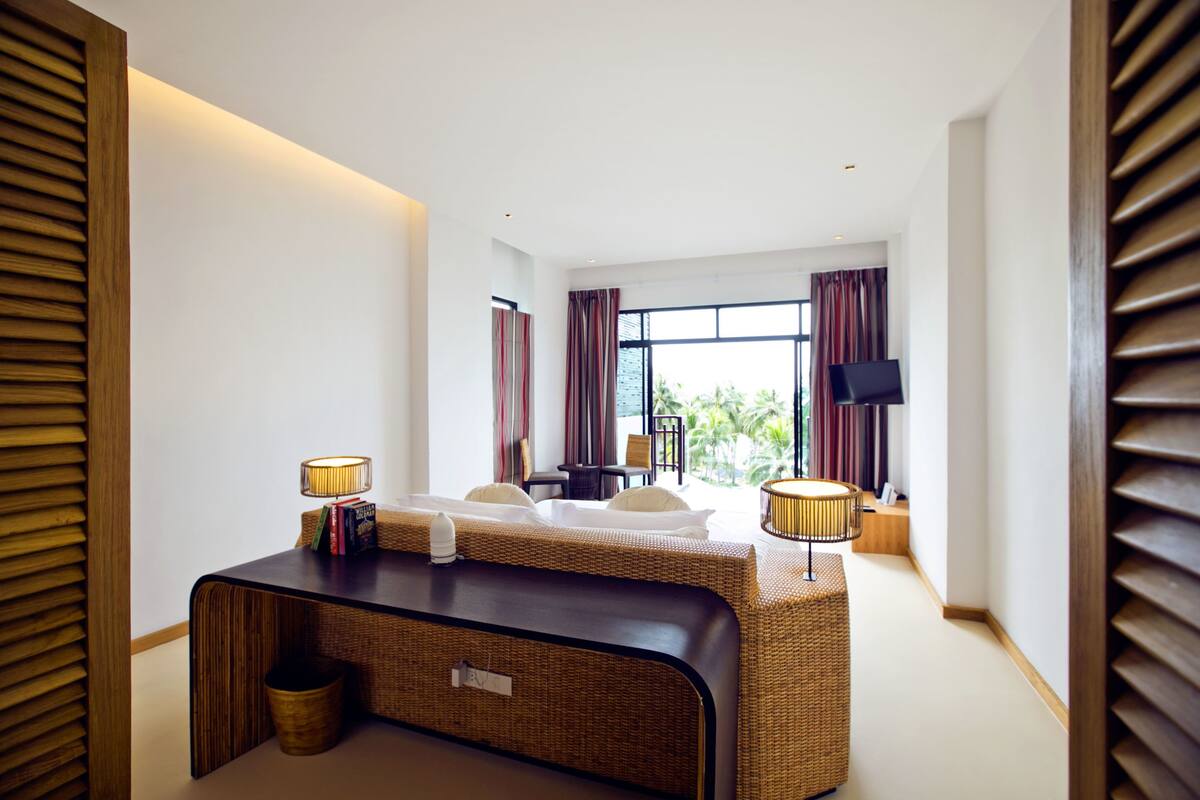 A modern hotel room with a large bed, a desk, and a TV.