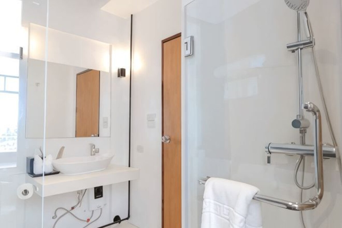 A modern bathroom with a glass shower enclosure, a white sink, and a mirror.