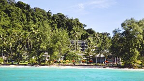 A beachfront hotel with a view of the ocean and dense tropical trees. - Ajinta Resort (Ko Kood)